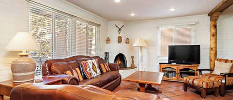 A living room with a leather sofa, a wooden coffee table, and a television.