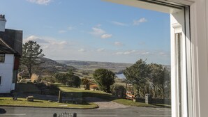 A view from a window overlooking a rural landscape with a road, grassy areas, and trees.