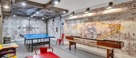 Et rum med et ping pong-bord, et bordfodboldbord og et billardbord.