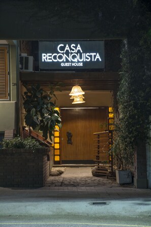 Indgangen til Casa Reconquista Guest House, med en trædør, en hængende lampe og et skilt over døren.