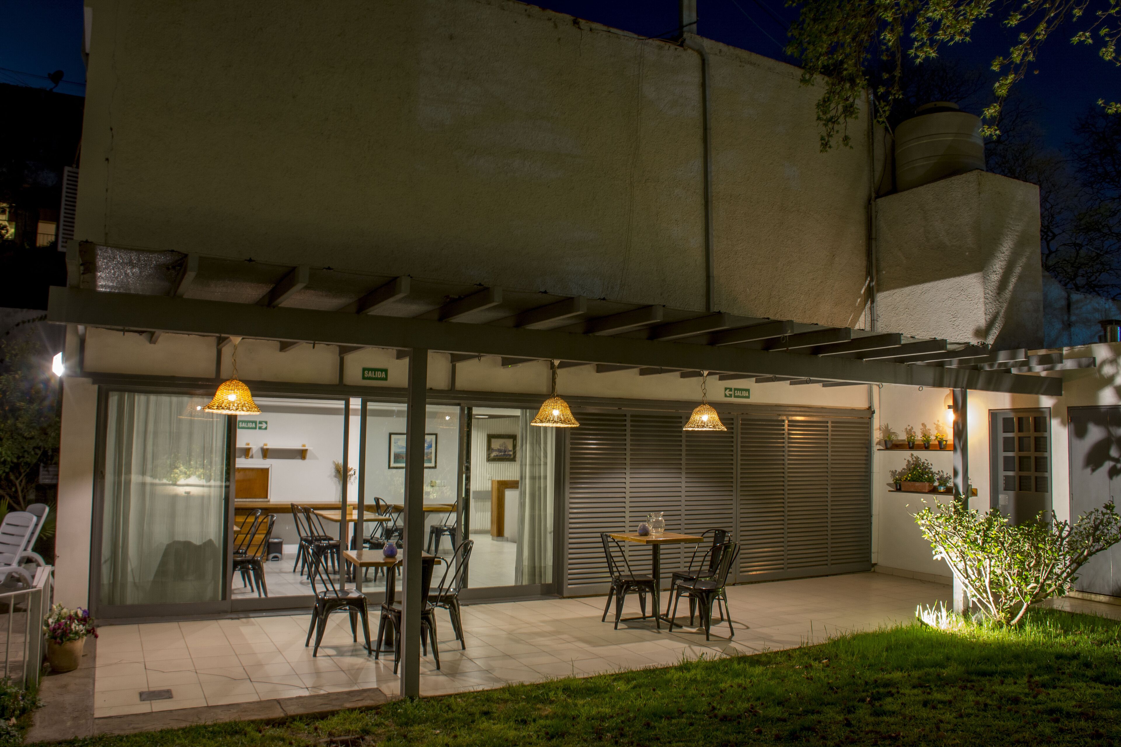 Une terrasse extérieure avec des tables et des chaises, un espace salon couvert et une porte de garage.