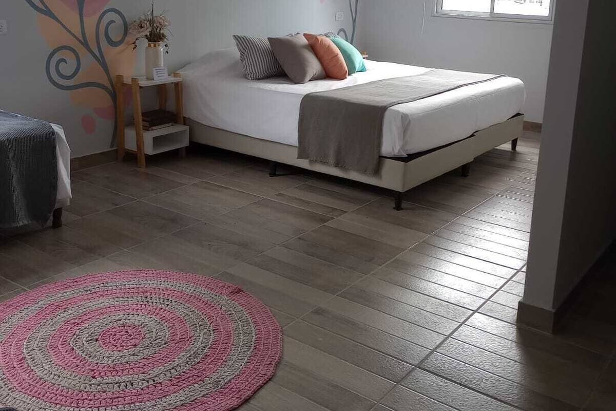 A bedroom with a bed, a nightstand, a window, and a decorative wall mural.