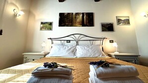 A bedroom with a bed, two nightstands, wall-mounted lamps, and framed pictures. - IL PIANETTO (Pieve Fosciana)