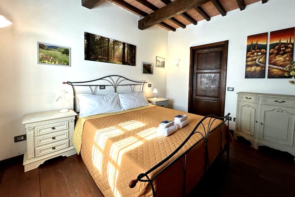 Un dormitorio con cama, mesitas de noche, armario y obras de arte en las paredes.