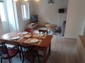 A dining area with a wooden table set for four, chairs, and a television in the background. - 1 Bedroom Private vacation home in Lembras (Lembras)