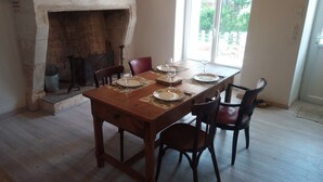 A dining room with a wooden table set for four, a fireplace, and a view of the outdoors. - 1 Bedroom Private vacation home in Lembras (Lembras)