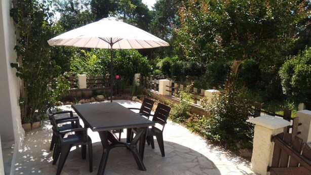 A patio with a stone table and chairs, an umbrella, and a wooden fence. - 1 Bedroom Private vacation home in Lembras (Lembras)