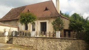 A two-story house with a tiled roof, a stone wall in front, and a wooden fence. - 1 Bedroom Private vacation home in Lembras (Lembras)