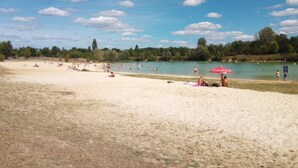 A beach with people sunbathing and swimming, a sandy shore, and a clear sky. - 1 Bedroom Private vacation home in Lembras (Lembras)
