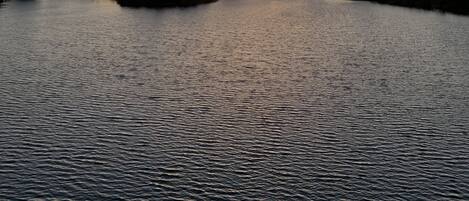 Ein Sonnenuntergang über ruhigem Wasser mit einer fernen Küste.