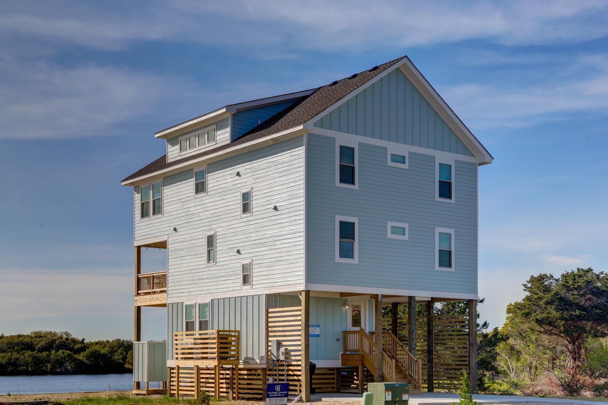 A two-story house with a balcony, a covered porch, and a wooden deck.