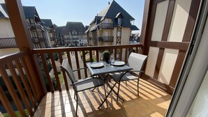 Un balcon avec une table et des chaises, donnant sur un quartier résidentiel avec des maisons traditionnelles.