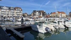 Un port de plaisance où sont amarrés des bateaux, entouré d’immeubles à plusieurs étages présentant différents styles architecturaux.