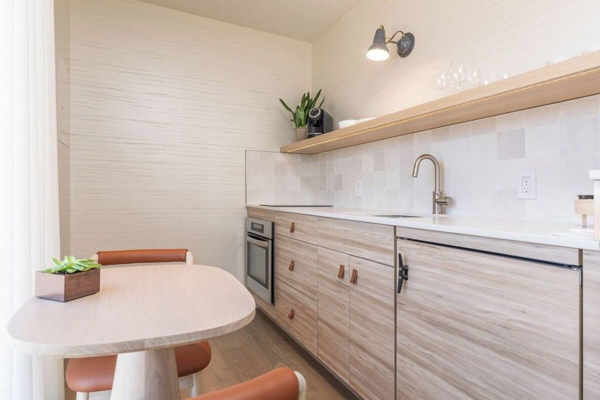 A modern kitchen with a round table, wooden cabinets, and a built-in oven.