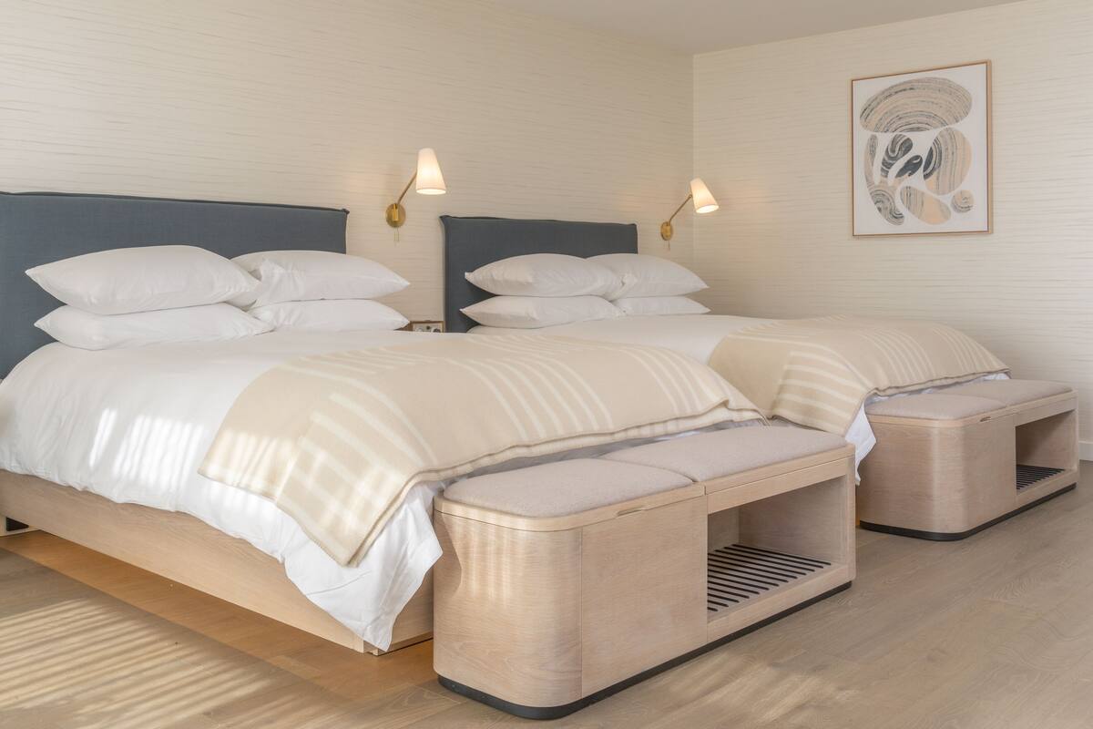 A modern bedroom with a large bed, bedside tables, and a bench.