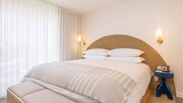 A neatly made bed with a headboard, two bedside lamps, and a small table with a radio.