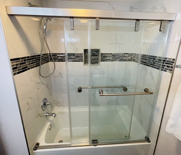 Una ducha envuelta en cristal con tres cabezales de ducha manuales.