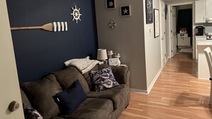 A living room with a dark blue accent wall, wooden furniture, and nautical-themed decorations.
