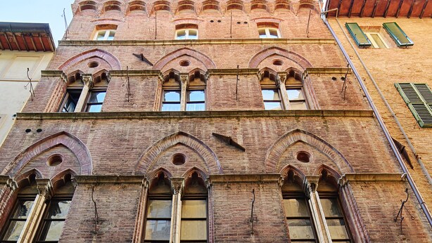Un edificio histórico con ventanas de arco y puerta de madera.