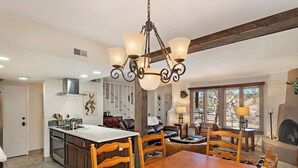 Uma cozinha ampla com uma ilha central, uma sala de jantar com cadeiras de madeira e uma lareira na sala de estar.