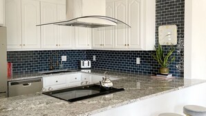 A modern kitchen with white cabinets, a black and blue backsplash, a stainless steel kettle, and a bar area with stools. - Geo Dome - Unique Urban Getaway – one of a kind! (Springfield)