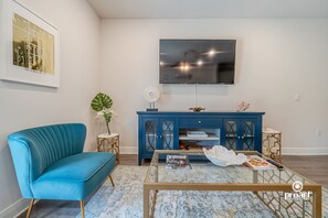 A living room with a blue sofa, a coffee table, a TV, and a blue cabinet.