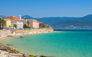 A coastal town with a beach, buildings, and mountains in the background.
