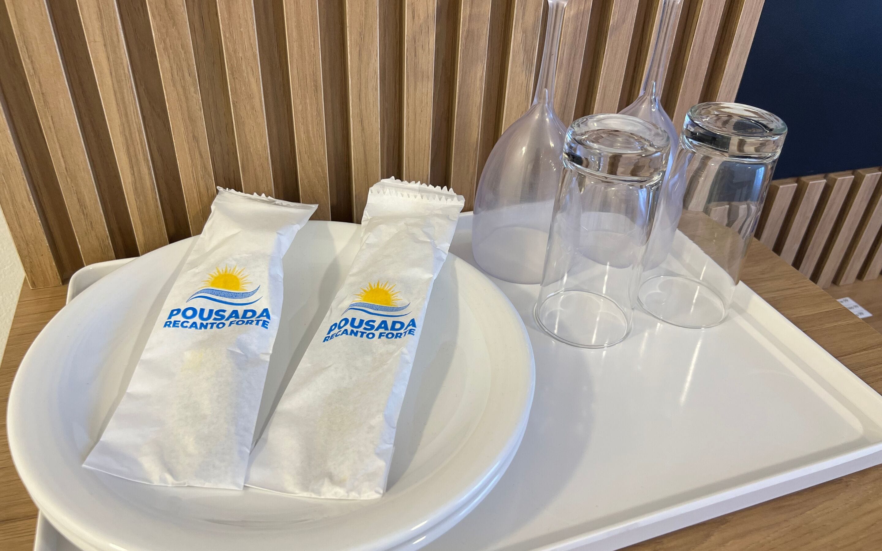 A tray with two packages labeled 'Pousada Recanto Forte' and two empty glasses.