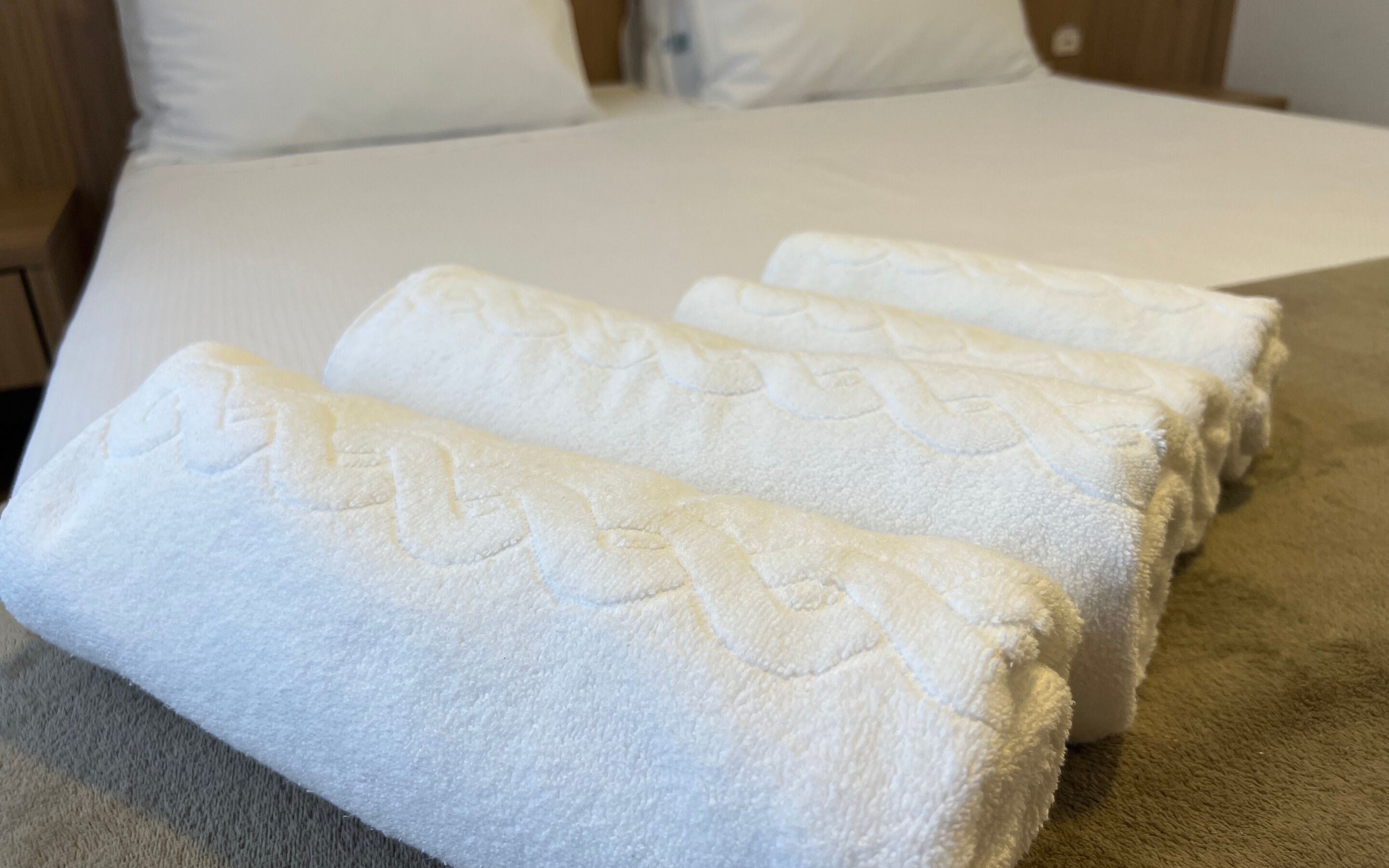 A neatly made bed with white linens and a textured blanket.
