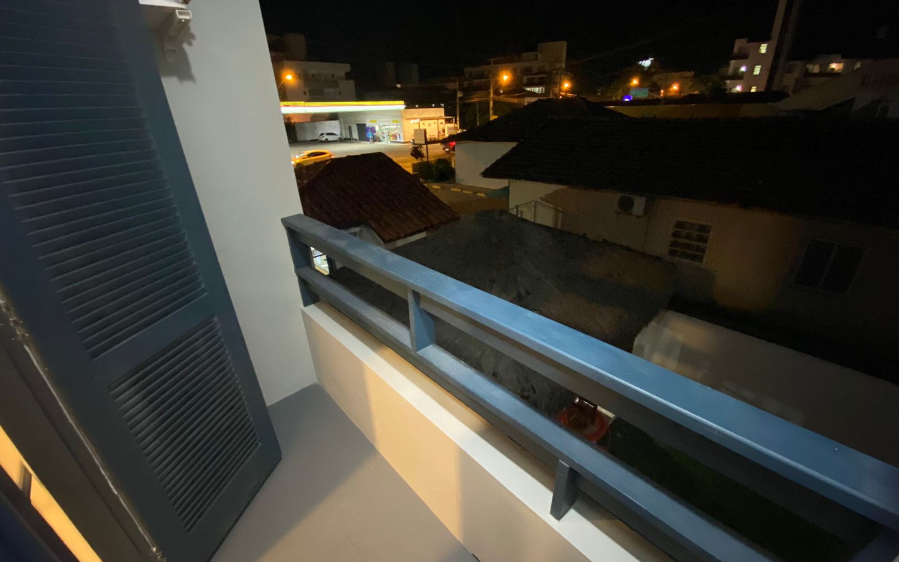 A balcony with a railing overlooking a street at night.