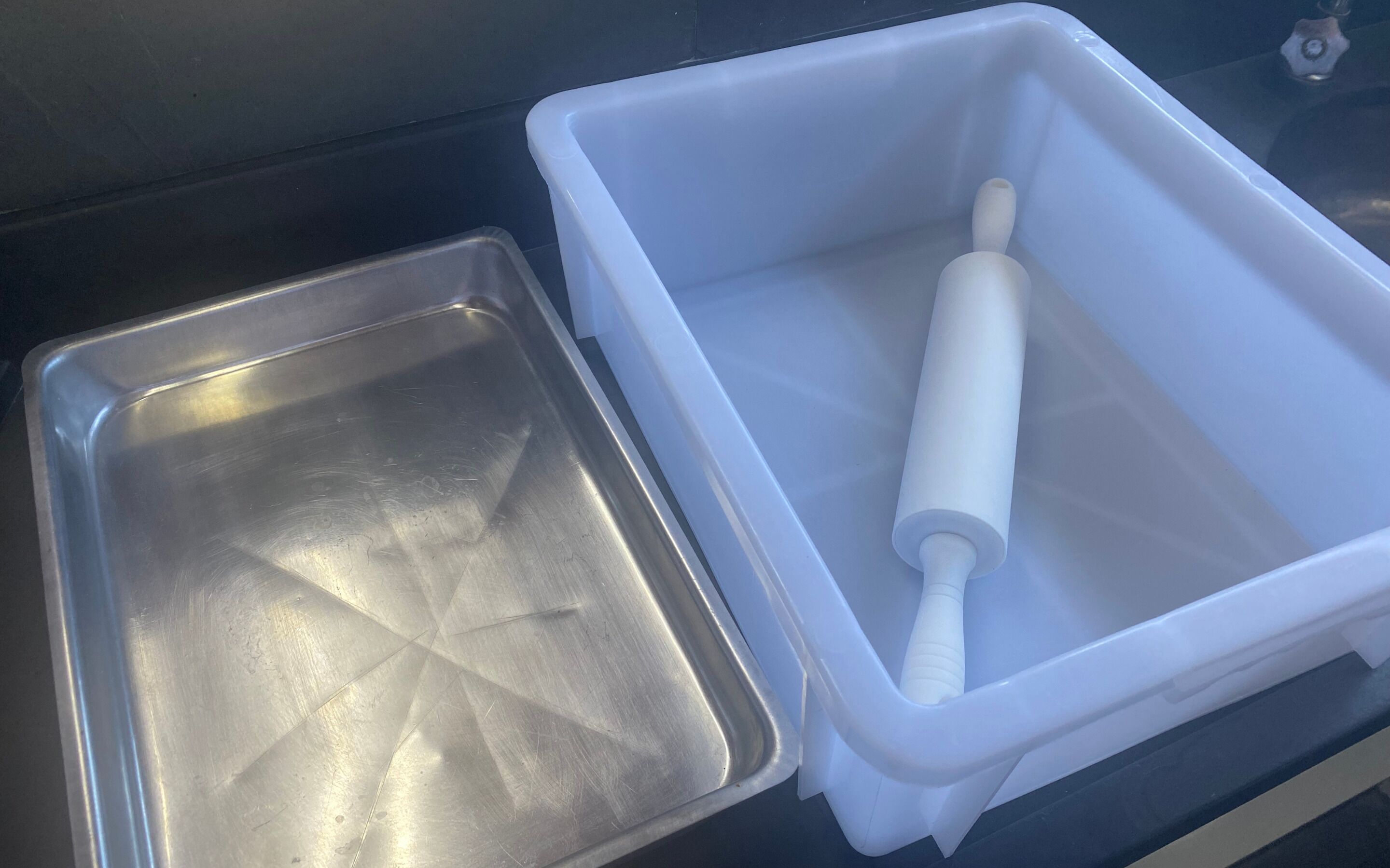 A stainless steel tray and a white plastic container with a white object inside.