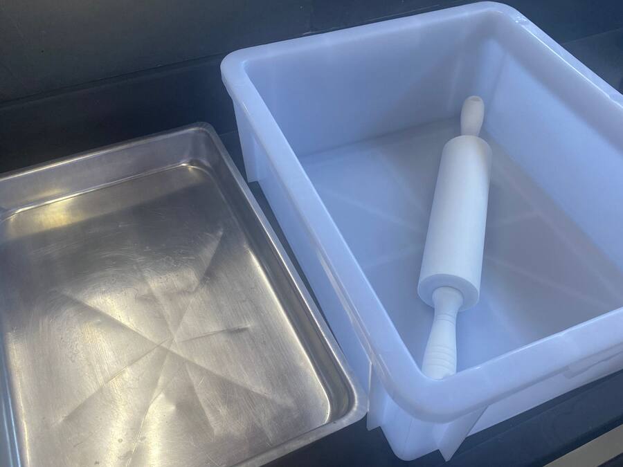 A stainless steel tray and a white plastic container with a white object inside.