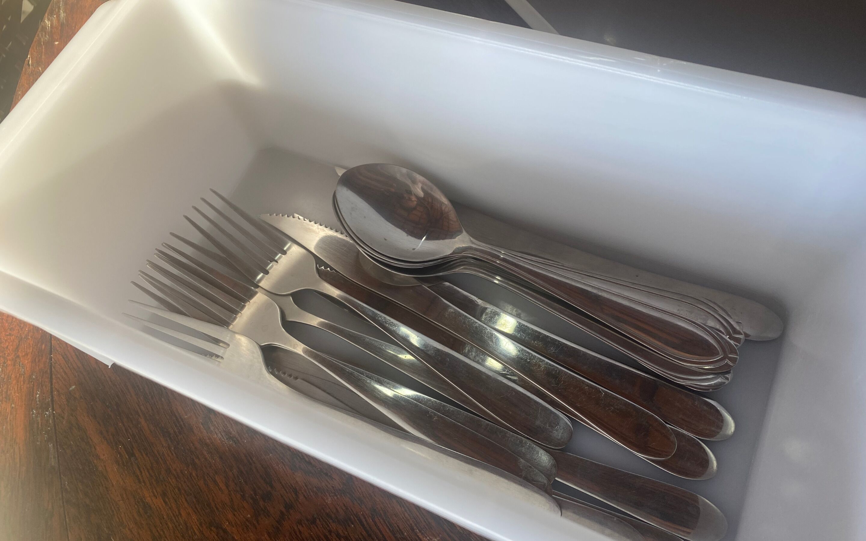 A white drawer containing a set of silverware including forks, knives, and spoons.