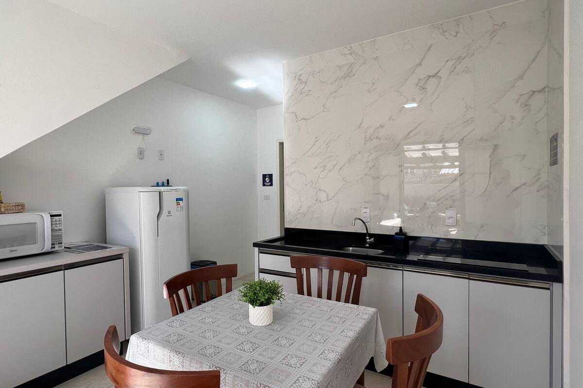 A compact kitchen with a microwave, refrigerator, and a dining table with chairs.