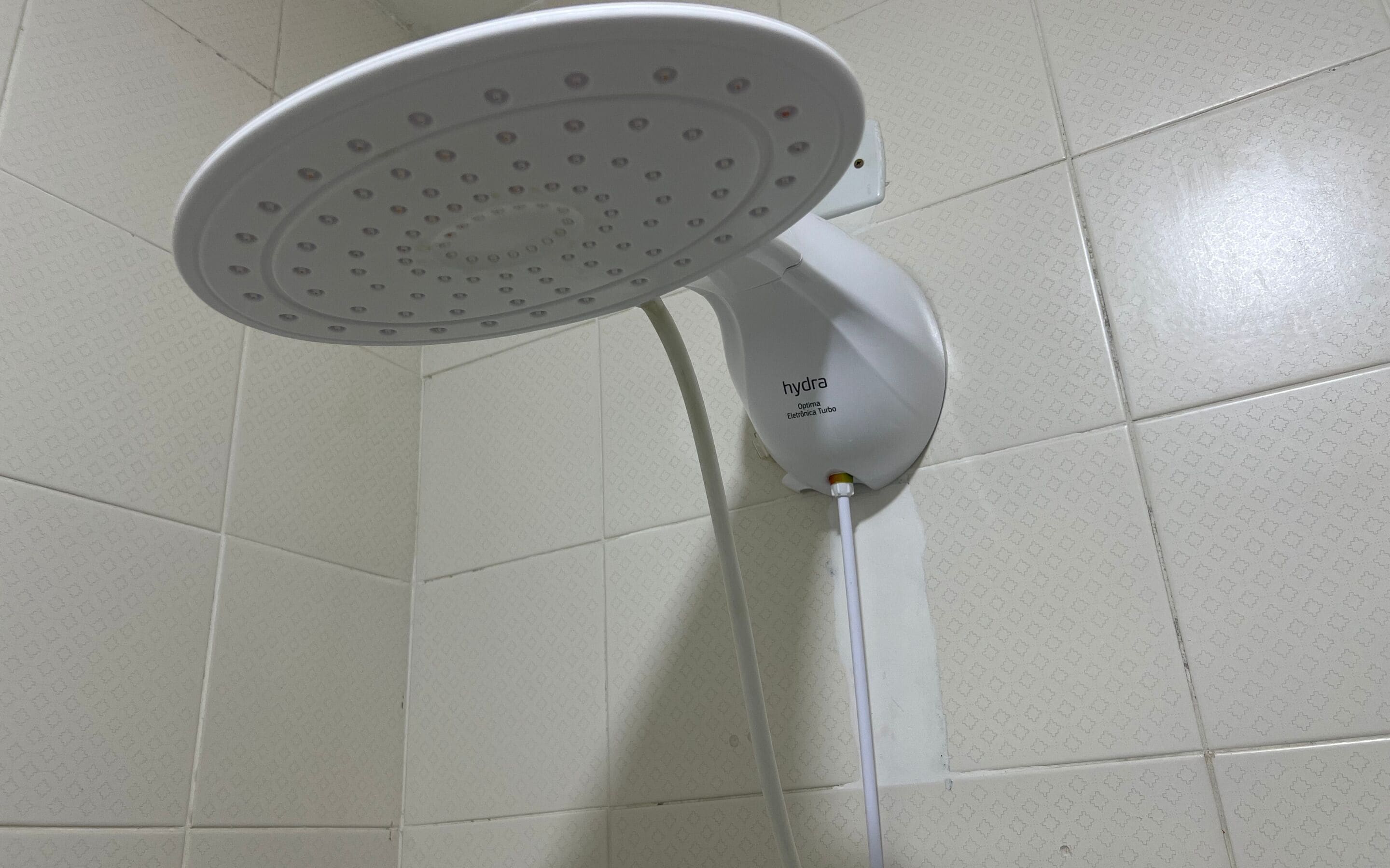 A white showerhead with multiple nozzles, attached to a wall-mounted fixture.