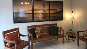 Una sala de estar con un banco de madera, dos sillones y una lámpara de pie.