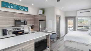 Een moderne keuken met een groot eiland, een magnetron, oven en koelkast. Boven het eiland hangt een bordje met de tekst 'The Best Days Are Lake Days'.