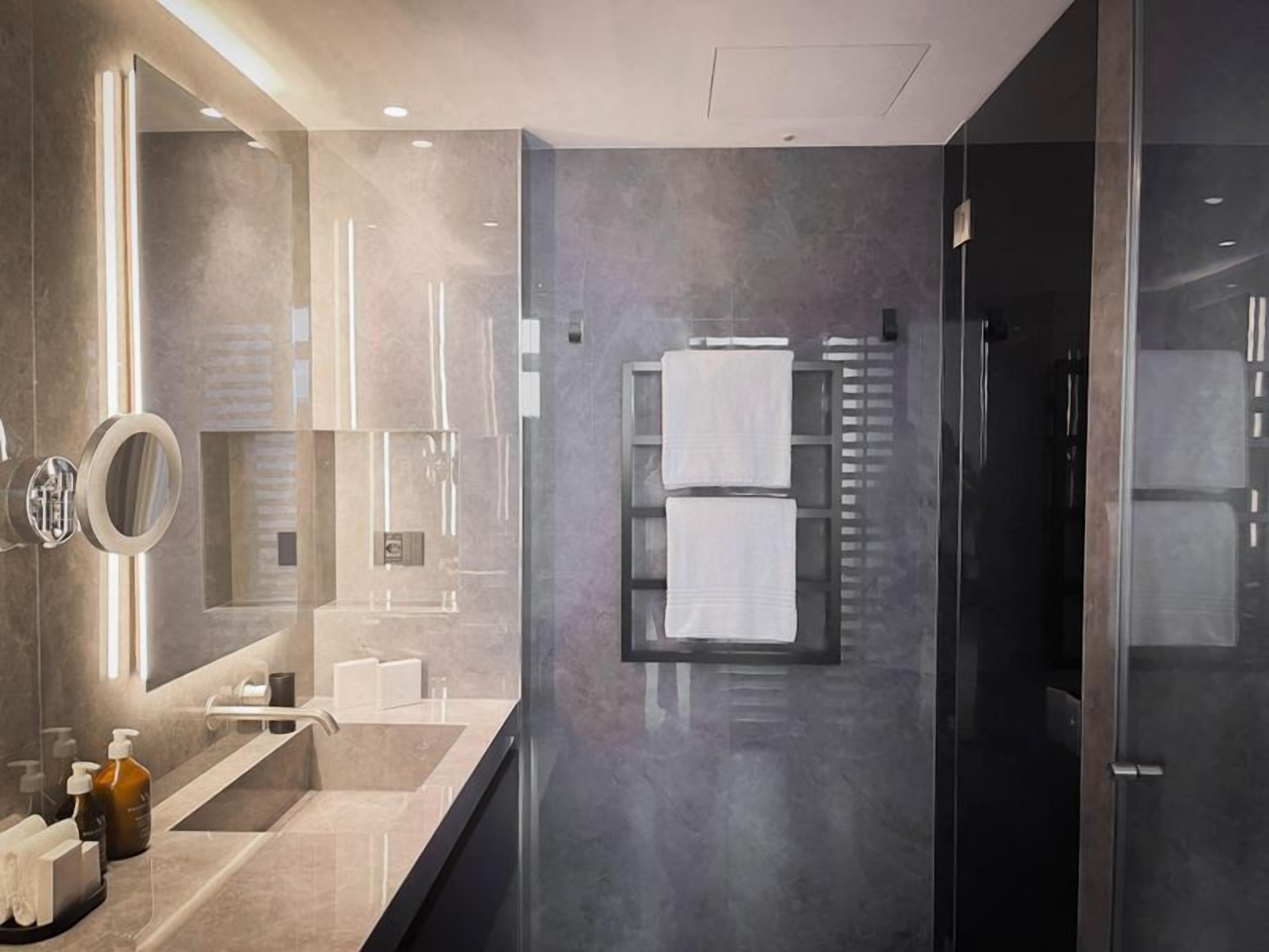 A modern bathroom with a large mirror, a glass shower enclosure, and a towel rack.