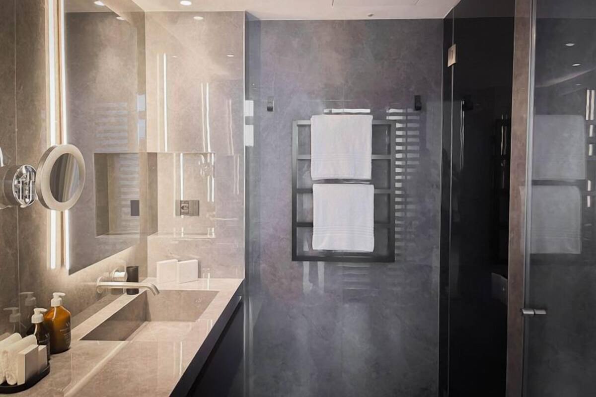 A modern bathroom with a large mirror, a glass shower enclosure, and a towel rack.