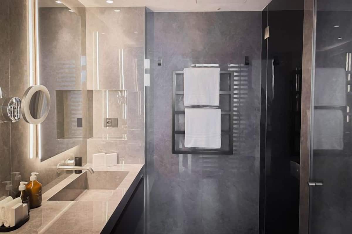 A modern bathroom with a large mirror, a glass shower enclosure, and a towel rack.