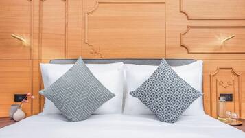 Ein Bett mit zwei gemusterten Kissen, einem Holzkopfstück und einem Nachttisch mit einer Vase und Gläsern.