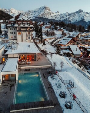 Un complexe hôtelier doté d’une piscine, entouré de paysages enneigés et offrant une vue sur les montagnes.