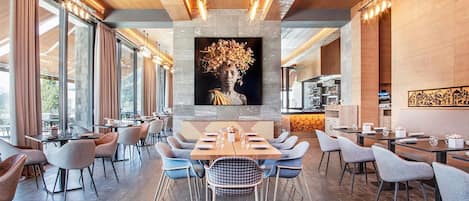 Un espace de salle à manger moderne avec une table centrale, entourée de chaises, et une grande œuvre d’art accrochée au mur au-dessus.