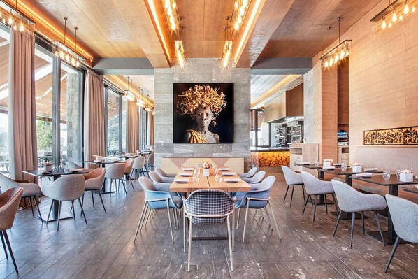 A modern dining area with a central table, surrounded by chairs, and a large wall-mounted artwork above.