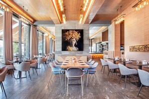 A modern dining area with a central table, surrounded by chairs, and a large wall-mounted artwork above. - Villars Palace (Ollon)