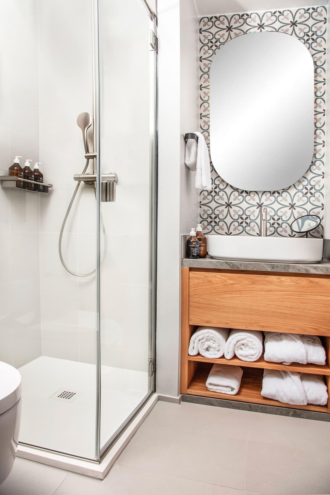 Ein modernes Badezimmer mit einer gläsernen Dusche, einem weißen Waschbecken und einem Holzlagerplatz für Handtücher.