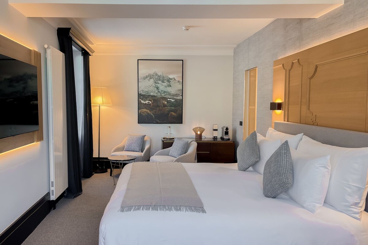 Une chambre d’hôtel moderne dotée d’un grand lit, d’un téléviseur à écran plat, d’un bureau avec une lampe et d’un tableau au mur.
