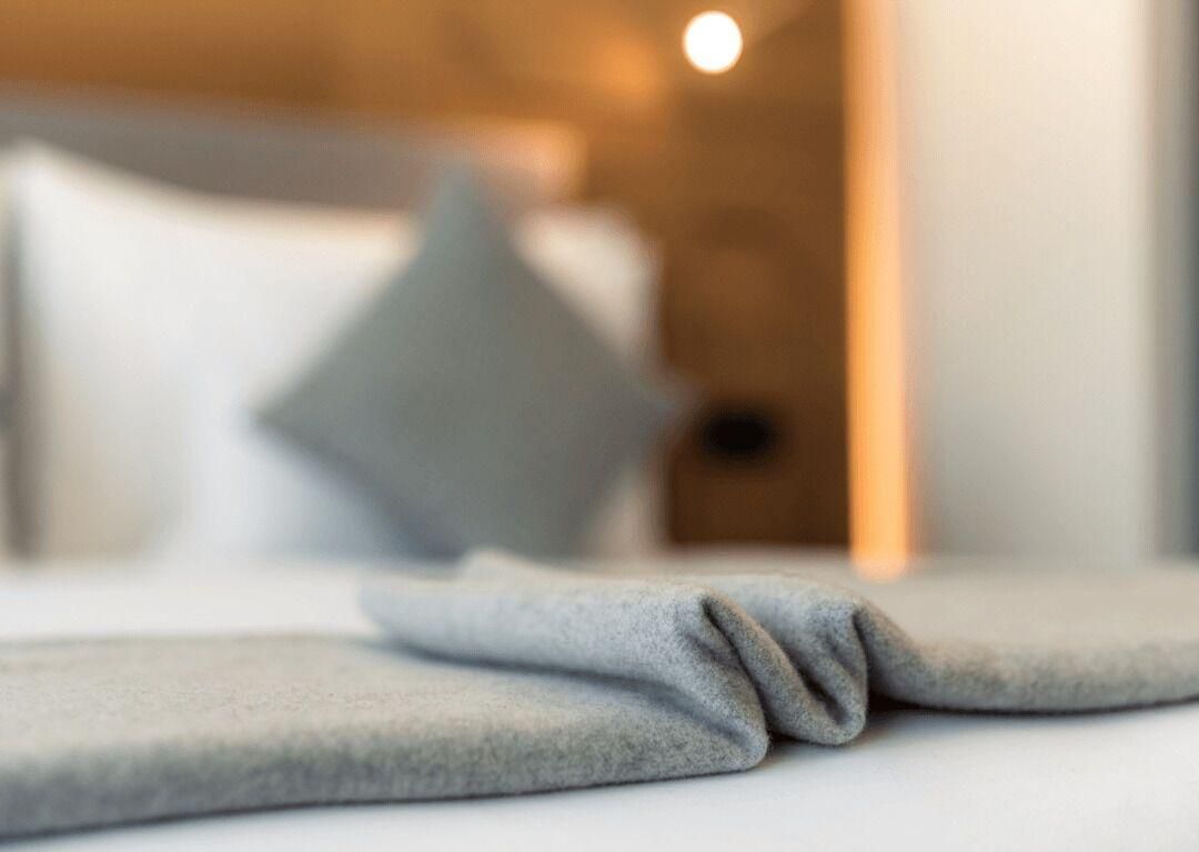 Ein verschwommenes Hotelzimmer mit einem Bett und einem Kissen.