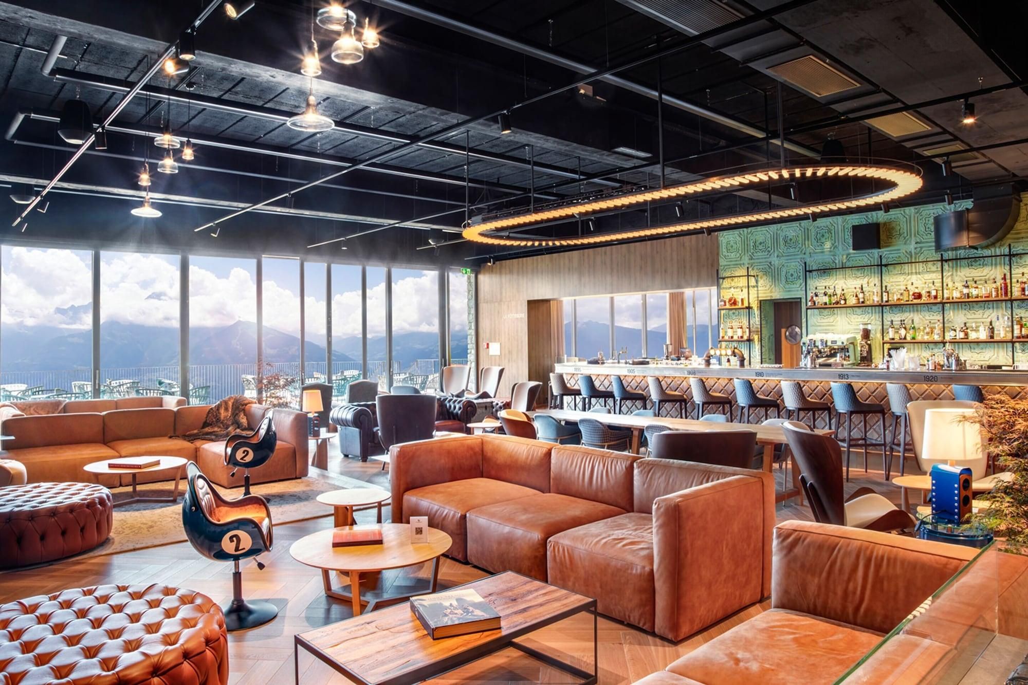 Un salon moderne avec des canapés en cuir, un coin bar et une vue sur les montagnes.