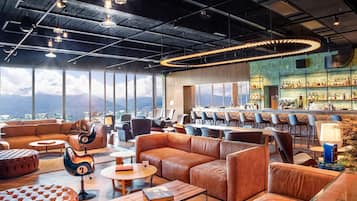 Un salon moderne avec des canapés en cuir, un coin bar et une vue sur les montagnes.